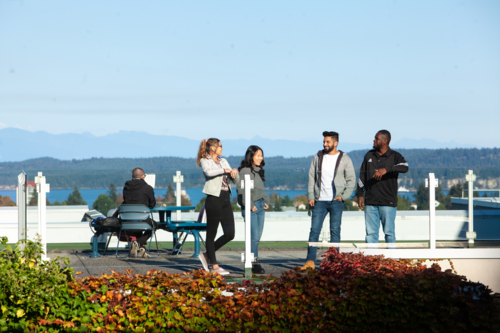 four students talking to each other on a VIU building rooftop