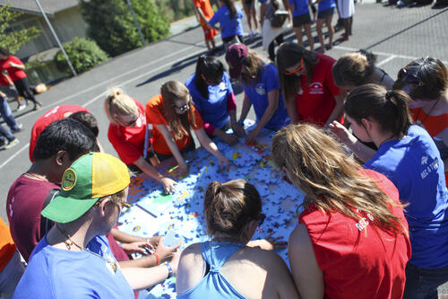 Group of people working on giant puzzle together.